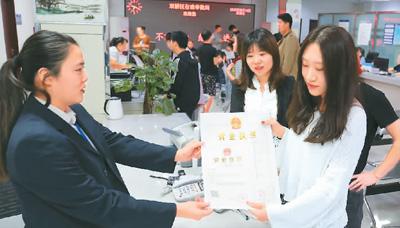 河北省承德市網(wǎng)絡(luò)代購經(jīng)營者陳晨(右)從工作人員手中接過帶有統(tǒng)一社會信用代碼的營業(yè)執(zhí)照。 劉環(huán)宇攝(人民圖片)
